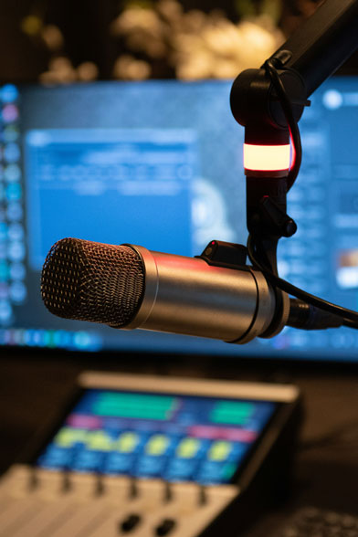 Photo of a microphone with broadcasting equipment in the background.
